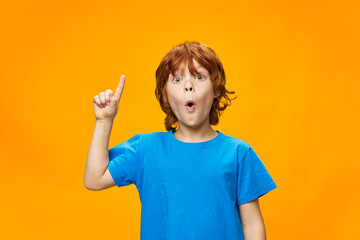 The red-haired child shows a thumb up and a blue T-shirt 