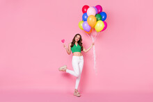 Full Body Photo Of Positive Cheerful Girl Hold Balloons Heart Shape Lollipop Enjoy Festive Occasion Party Wear Green White Pants Isolated Over Pastel Color Background