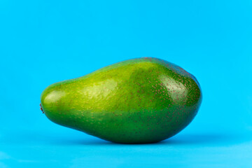 Ripe fresh green avocado on blue background