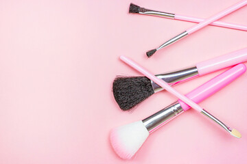 Top view of bright pink decorative cosmetics tools and accessories for professional make up and visage on light background with copy space.