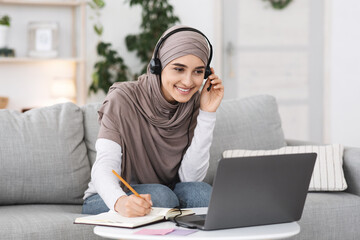 Wall Mural - Online Education. Smiling Arabic Gir Watching Webinar On Laptop At Home