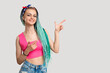 © golubovy - Woman with bright blue hair braids isolated pointing at neutral copy space. Cheerful lady in pink with creative hairstyle. Colorful promotional background.