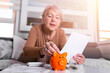 savings, money, annuity insurance, retirement and people concept - Senior woman hand putting coin into piggy bank. Happy Mature woman Calculating Coin In The Piggybank