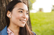 © Drobot Dean - Image of joyful asian student woman using wireless earphones and smiling