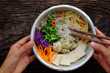 © xuanhuongho - Homemade Vietnamese vegan noodles soup with colorful vegetables, people hand hold bowl to ready to eat
