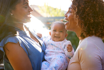 grandmother with adult daughter and baby granddaughter playing in garden at home together