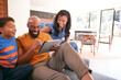 © Monkey Business - African American Family With Son Sitting On Sofa At Home Using Digital Tablet