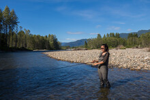 An Asian Women In Waders, Enjoying Fishing A River In British Columbia, Canada