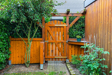 Wooden gate and fence on the back of the home garden. The gate is closed with a padlock.