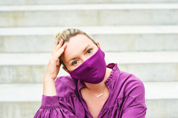 Wall Mural - Outdoor fashion portrait of pretty woman wearing purple blouse and facemask