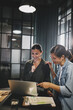 © Flamingo Images - Two smiling businesswomen working on a laptop in an office