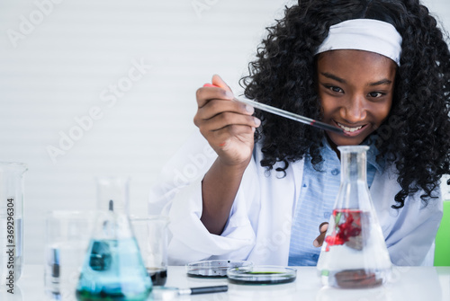 African american child girl student is learning and test science chemical with colorful liquid in beaker