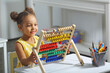 © ShunTerra - an african-american girl sits at a table and counts on an abacus