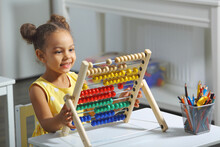 An African-american Girl Sits At A Table And Counts On An Abacus