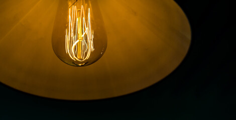 Closeup of light bulb on the wall, turned on lamp on the ceiling,  idea concept, power and electricity, save the energy and turn off the lights