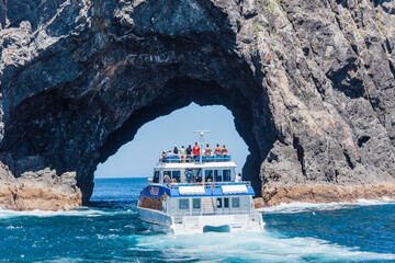 tour boat entering the hole in the rock in bay of islands, new zealand