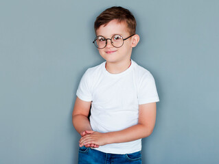 Photo of adorable young happy boy wearing white t-shirt looking at camera over grey background