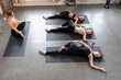 © fStop - Yoga instructor and students practicing supine spinal twist in yoga class