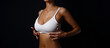 Slim sporty girl front taned body in white underwear straightens the top under the bust close-up with the black background text space around