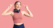 © Krakenimages.com - Beautiful caucasian young woman wearing gym clothes and using headphones smiling amazed and surprised and pointing up with fingers and raised arms.