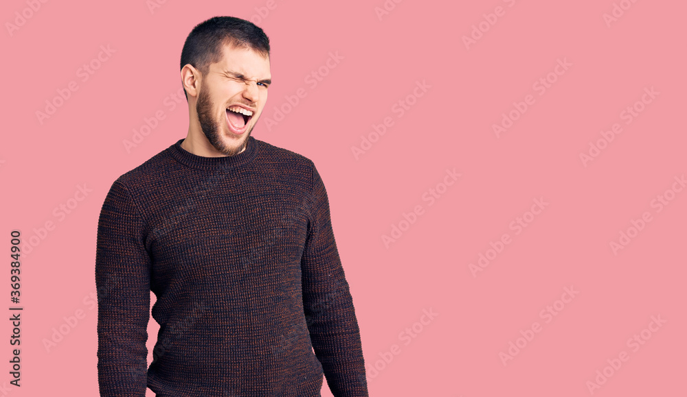 Young handsome man wearing casual sweater winking looking at the camera with sexy expression, cheerful and happy face.