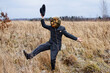 a monstrous Scarecrow with a Halloween pumpkin on his head dancing in a wild field dressed in a business suit