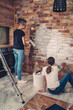 © kerkezz - mom and daughter are painting a brick wall in the kitchen