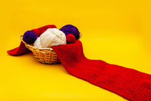 Blue And White Skeins Of Thread Lie In A Wicker Basket, Which Also Contains A Red Knitted Scarf. Orange Background,