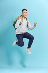 Wall Mural - Happy young attractive man jumping and waving his hand, wearing in basic clothes with backpack