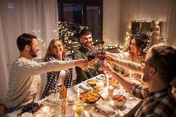 Wall Mural - holidays, celebration and people concept - happy friends having christmas dinner at home drinking non-alcoholic red wine