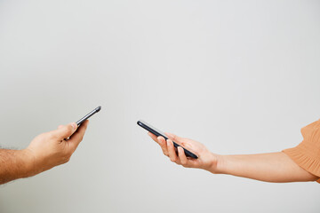 A male and female hands with phones opposite each other