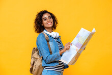 Young Amazed African American Woman Tourist Backpacker Holding World Map On Yellow Studio Background