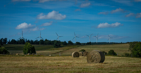 straw bales in field with wind farm on the horizon. Lozere ,France.