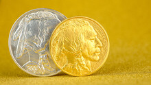 Silver And Golden American Buffalo One Ounce Coins Laying On Silver And Golden Background.