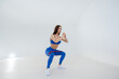 © Andrii - Sexy young girl performs sports exercises on a white background. Fitness, healthy lifestyle