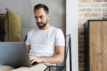 Wall Mural - Serious man indoors at home using laptop computer