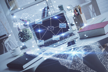 Desktop computer background in office and flying envelops hologram drawing. Double exposure. Electronic mail concept.