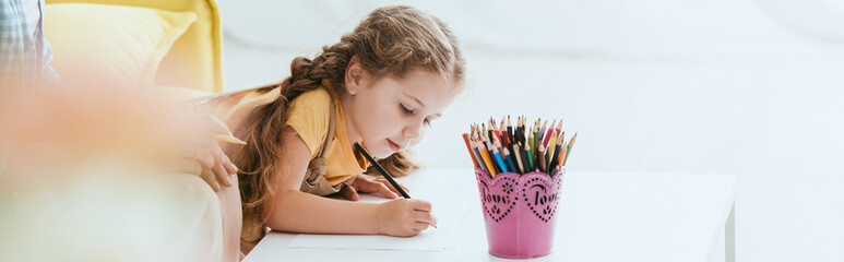 Wall Mural - cropped view of nanny near adorable child drawing with pencil, horizontal image