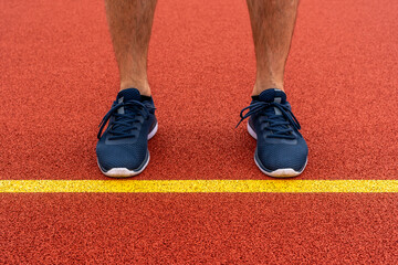 Wall Mural - Man standing behind the yellow line in the sports ground