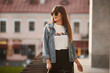 Model girl in a denim jacket and rounded sunglasses walking outdoors in the summer evening