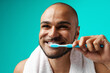 © fotofabrika - Cheerful dark-skinned male brushing his teeth against turquoise background