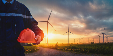 technician engineer in uniform and holding orange safety helmet with standing and checking wind turb
