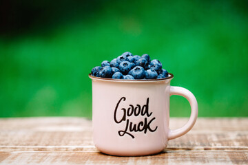 Wall Mural - Fresh juicy blueberries in a pink cup with the inscription 