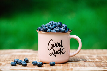 Wall Mural - Fresh juicy blueberries in a pink cup with the inscription 