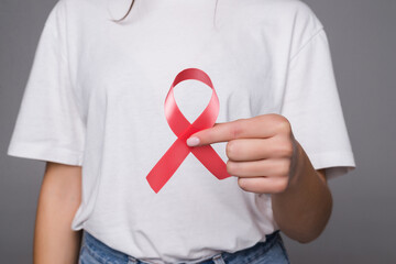 Woman holding breast with pink ribbon over white background. Concept photo to support breast cancer cause.