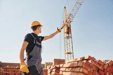 Communicating with crane guy. Construction worker in uniform and safety equipment have job on building