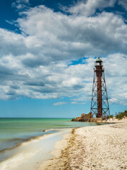 Wall Mural - view to old metal lighthouse on the beach of sand island at the Black sea under clouds with copy space