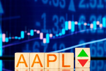 aapl. wooden cubes with the inscription aapl and a cube symbolizing the rise and fall of the financial market against the background of the stock chart