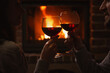 © New Africa - Couple with glasses of red wine near burning fireplace, closeup