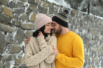 Wall Mural - Lovely couple wearing warm sweaters and hats outdoors on snowy day. Winter season